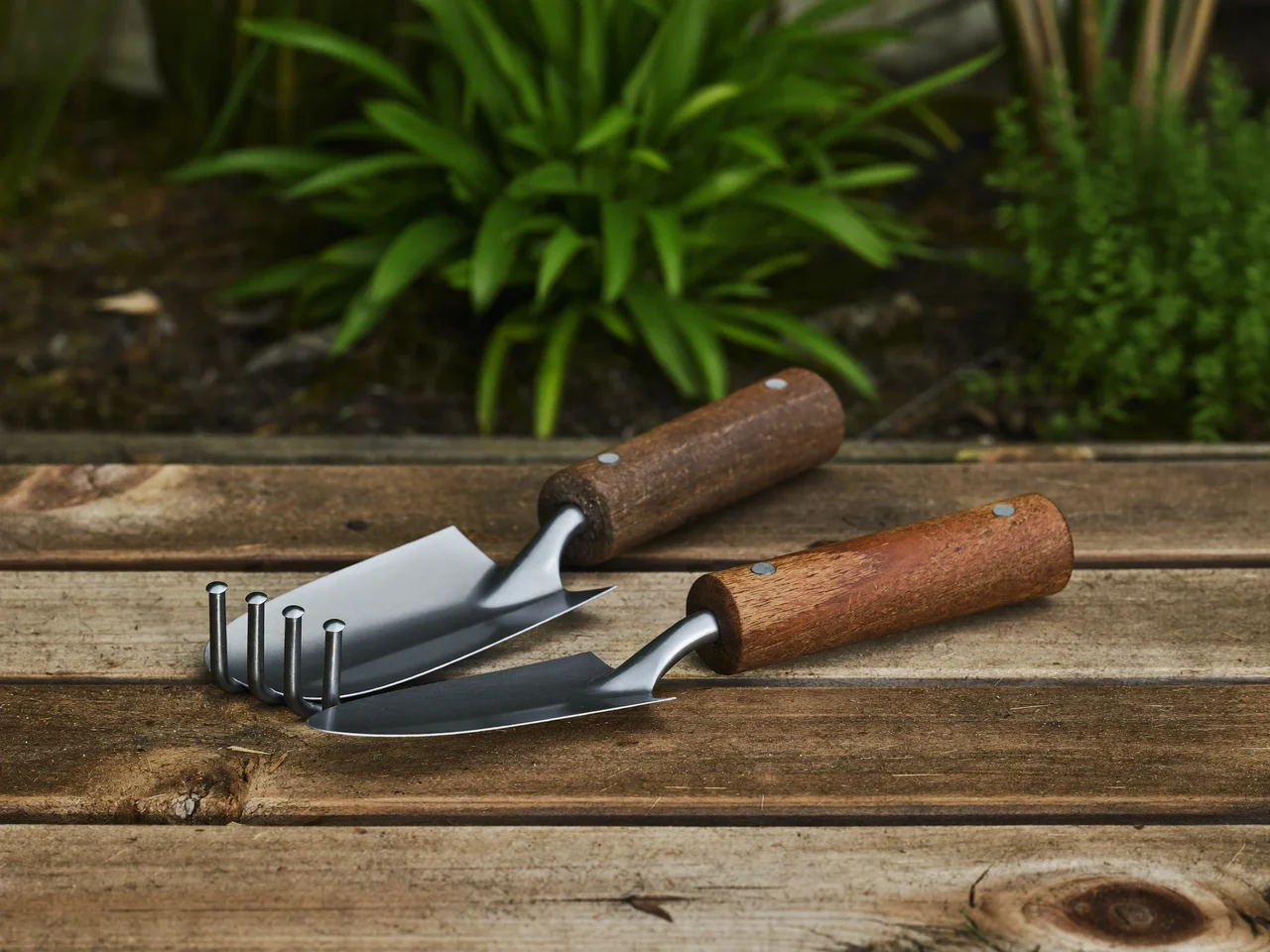 Zappetta e coltivatore con manici in legno imbottiti su una panca da giardino